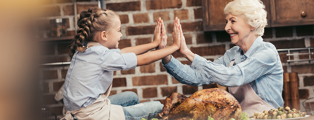 Image of grandmother and granddaughter touching hands at the dinner table